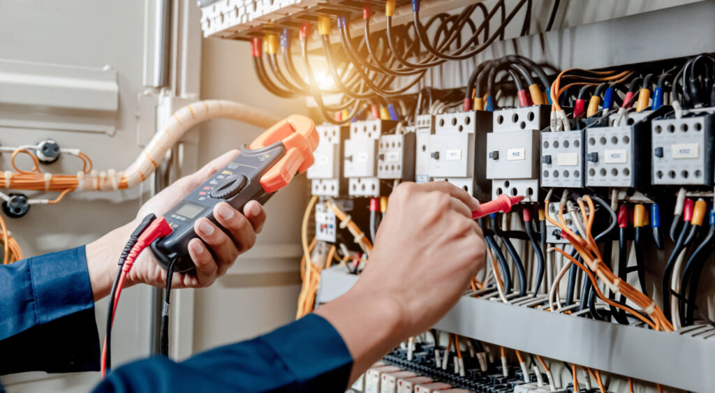 Elektro Rot GmbH Schaltschrank Ein Elektriker verwendet ein Multimeter, um die elektrische Installation und den Stromleitungsstrom in einem Schaltschrank für ein elektrisches System zu testen.